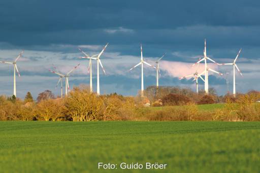 Windpark in Mecklenburg-Vorpommern bei Aprilwetter. Vordergrund: Grünes Getreidefeld, Himmel Dunkle Wolken.
