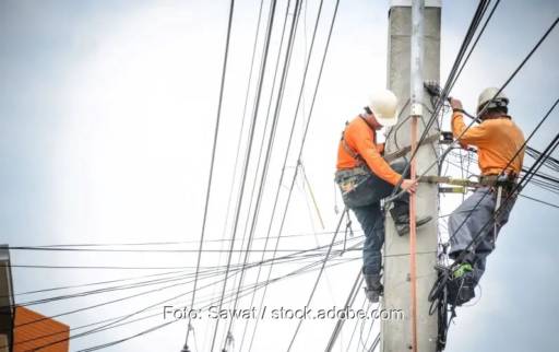 Zwei Männer auf einen Strommast als Symbol für den Stromnetzengpass in Oranienburg.