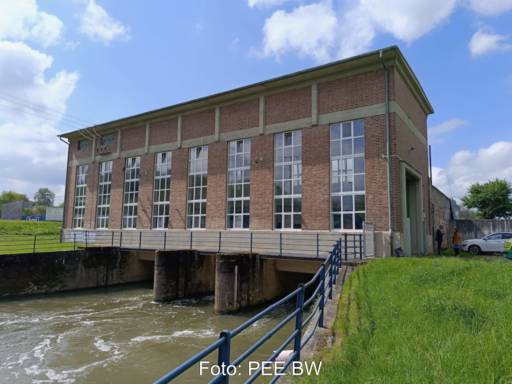 Foto zeigt Backstein-Gebäude, das über einem Fließgewässer errichtet ist - ein Wasserkraftwerk.