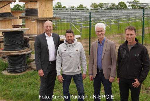 4 Personen auf einer Wiese mit installierten PV-Gestellen und Kabeln auf Trommeln.