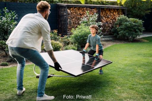 Das Bild zeigt einen Mann und ein Kind, die eine Steckersolaranlage tragen, durch das Solarpaket entfällt für Balkonkraftwerke entfällt die Anmeldepflicht beim Netzbetreiber.