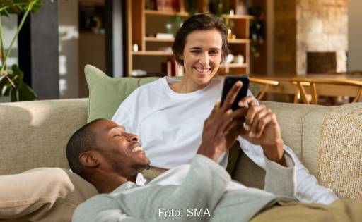 Im Bild ein Paar mit Smartphone. Ein dynamischer Stromtarif für Kunden von SMA soll Stromkosten senken.