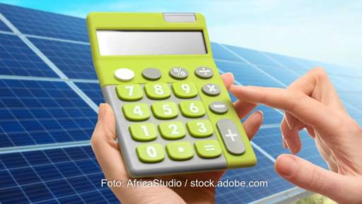 Ein Taschenrechner vor Photovoltaik-Anlage als Symbol für den Wertschöpfungsrechner für erneuerbare Energien.