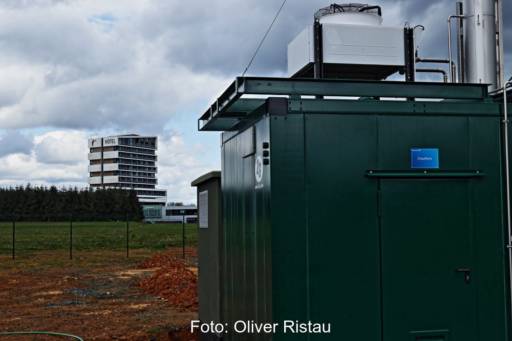 Ein mehrstöckiges Hotel im Hintergrund. Vorne steht die Wärmezentrale eines BHKWs.