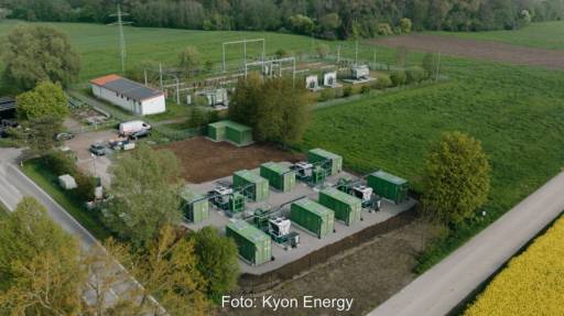 Luftbild zeigt Großspeicher mit zehn Batteriecontainern auf der grünen Wiese.