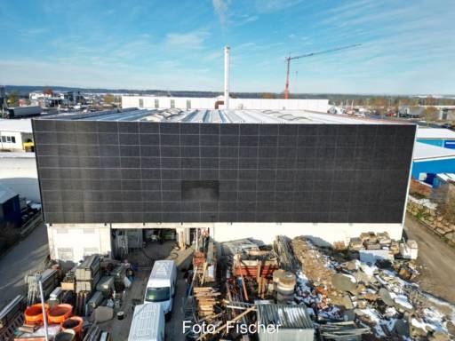 Vollflächige Solarfassade eines Bestrandgebäudes, davor Baufahrzeuge.