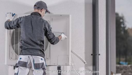 Im Bild ein Installateur, der eine Luft-Wärmepumpe installiert. Für die Berechnung der Jahresarbeitszahl von Wärmepumpen-Anlagen gibt es die VDI-EE 4650 Blatt 1.1.