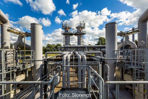 Eine Konstruktion aus grauen Pipelinen und Stangen mit zwei Männern in roter Weste im Hintergrund auf Türmen.