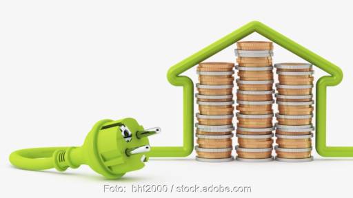 Münzstapel und ein grünes Kabel, das ein Haus bildet - Symbol für Strom- und Energiekosten.