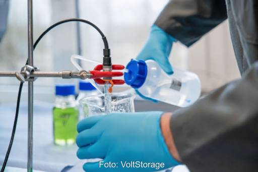 Person im Schutzanzug gießt in Laborumfeld Flüssigkeit um.