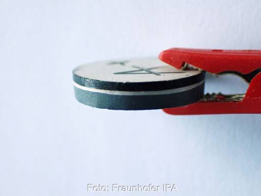 Eine Feststoffbatteriezelle, gehalten von einer Zange.