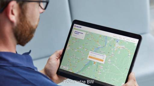 Mann schaut auf Tablet, das Landkarte zeigt - automatische Suche nach Netzanschluspunkt für Photovoltaik-Anlagen