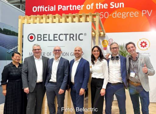 Sieben Frauen und Männer vor einem Messestand von Belectric.