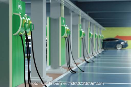 Lange Reihe von grünen Ladesäulen in einer Tiefgarage - im Hintergrund ein PKW.