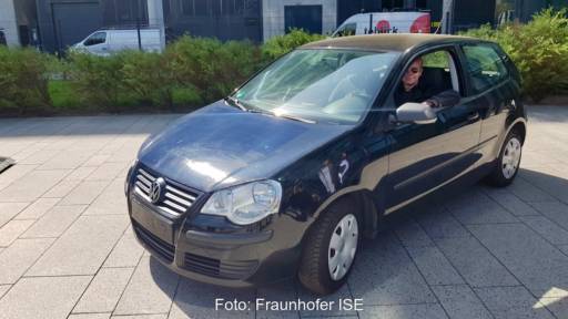 ein schwarzes Auto in dessen Motorhaube bei genauem Hinsehen Solarzellen erkennbar sind.