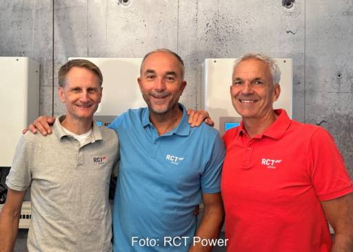 Drei Männer in Polo-Shirts vor einer Wand mit Stromspeichern: die Geschäftsführung von RCT Power.