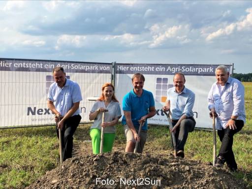5 Personen vor einem Aufsteller zu Agri-PV beim Spatenstich auf dem Land.