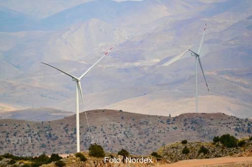 zwei Windenergie-Anlagen in trockenem, hügeligem Gelände