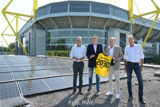 Vier Personen auf dem Stadiondach des BVB neben existierender PV-Anlage.