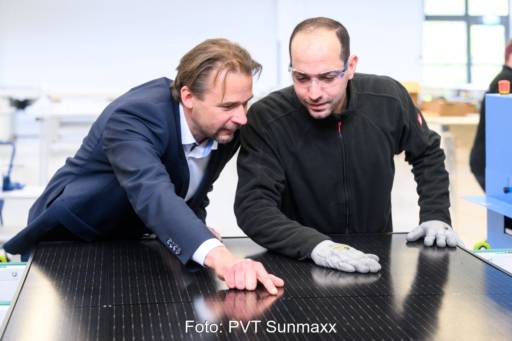 Zwei Männer prüfen in einer Halle ein PVT-Modul.