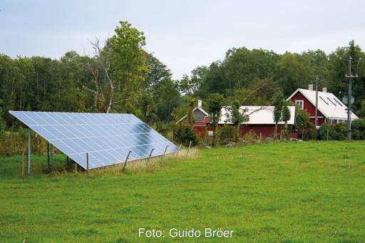 Garten-PV-Anlage vor einem roten Holzhaus