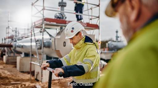 Zwei Arbeiter mit Schutzhelm und -weste am Standort einer Gaspipeline.