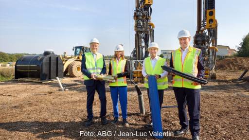 Im Bild Offizielle mit Baustellenhelm vor den die Geothermiebohrgerät im Klimaschutzquartier Hilgenfeld.