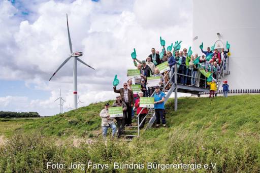 Menschengruppe am Fuß einer Windenergieanlage - Symbolbild für Bürgerenergie und Energy Sharing