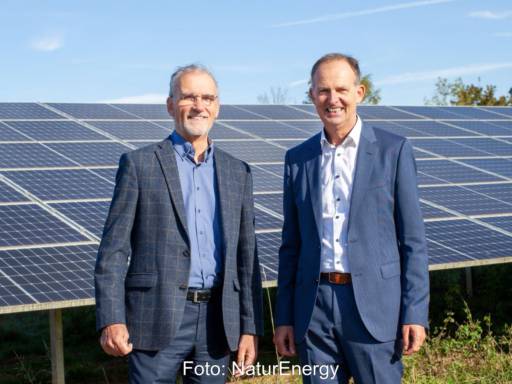 Zwei Männer in Anzügen vor PV-Anlage im Freien