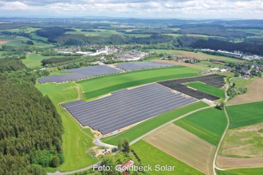 Luftbild zeigt mehrere Solarparks umgeben von Wiesen, Feldern und einer nahen Ortschaft.