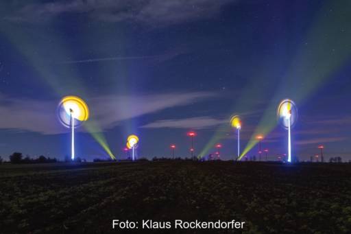 Kunst: Leuchten an Windenergieanlagen zeichnen bunte Bilder in den Nachhimmel.