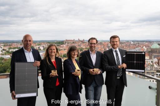 2 Frauen und drei Männer auf einem Hochhausdach mit Solarmodul