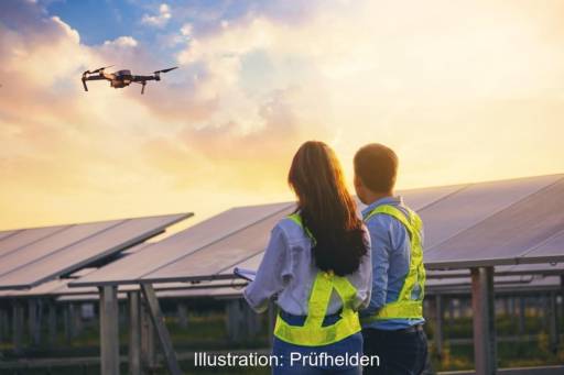 Ein Mann und eine Frau vor einer Photovoltaik-Anlage, darüber fliegt eine Drohne - Thermografie von Prüfhelden.