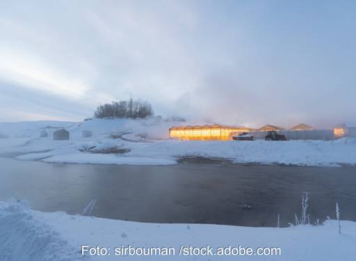 Hell beleuchtetes Gewächshaus in verschneiter Landschaft - Geothermie in Island, nicht in Bayern.