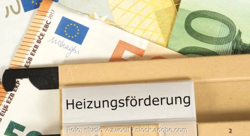 Ein Aktenordner mit der Aufschrift Heizungsförderung und Geldscheine, die BEG-Heizungsförderung läuft 2025 weiter.