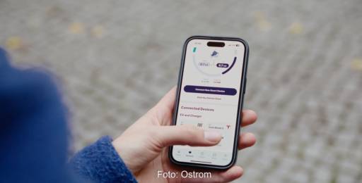 Im Bild eine Hahd mit Handy mit der Ostrom-App, über die man ein Virtuelles Kraftwerk für E-Autos nutzen kann.