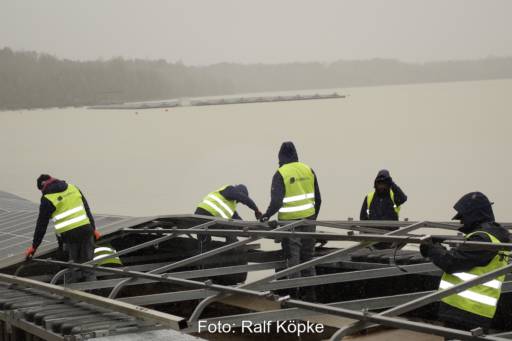 Installateure bei der Arbeit: Sie schrauben Photovoltaik-Module auf die schwimmende Pontons für eine Floating-PV-Anlage