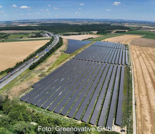 Luftbild eines Freiflächensolarparks an einer Autobahn.