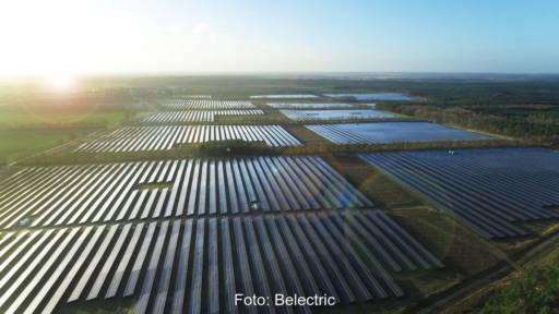 Luftbild eines raumgreifenden PV-Parks bei tiefstehender Sonne im Flachland.