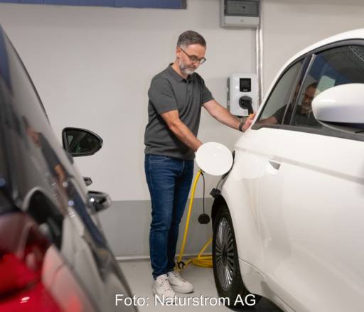 Mann lädt Auto mit Strom in einer Tiefgarage.