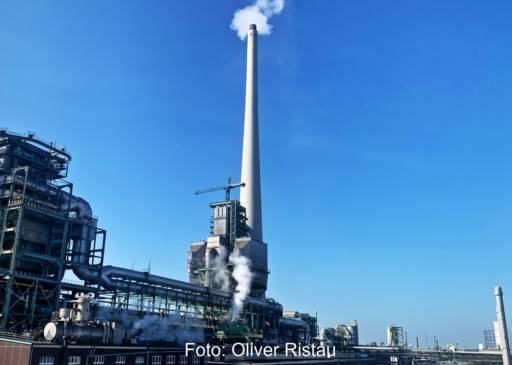 Schornstein einer Chemieanlage vor blauem Himmel.