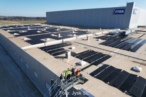 Dach eines Logistikgebäudes mit PV und winkenden Mitarbeitern.