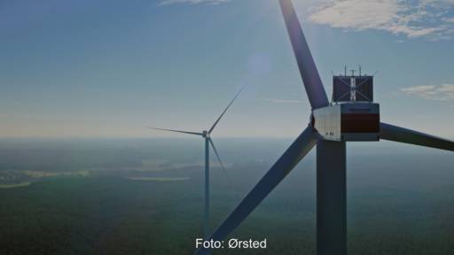 Gondel einer Windkraftanlage in. luftiger Höhe mit Blick auf Flachland in der Tiefe.