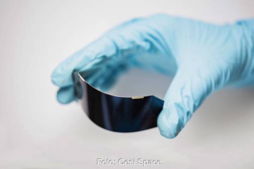 Hand mit Handschuh biegt eine flexible Solarzelle.