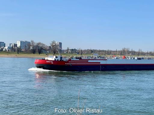Ein Binnenschiff fährt auf dem Rhein bei blauem Himmel.