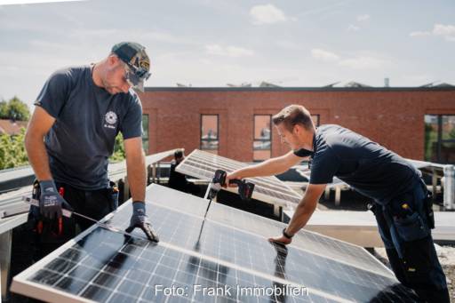Zwei Handwerker installieren eine Photovoltaikanlage auf einem Dach.
