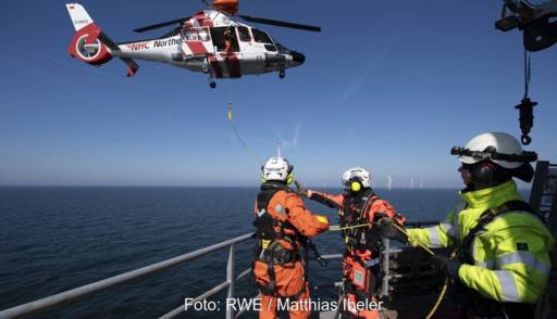 Ein Rettungshubschrauber und Menschen auf einem Schiff, RWE übt Rettung im Offshore-Windpark.
