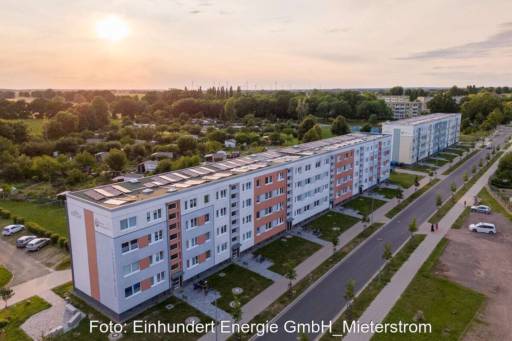 Sonnenuntergang über einer Wohnanlage in Landschaft mit Photovoltaik auf dem Dach