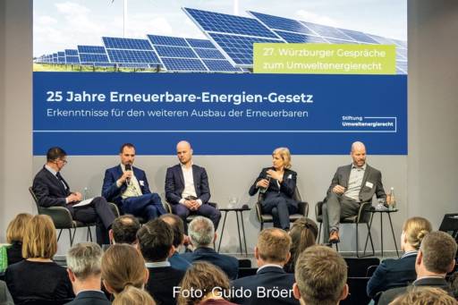 Blick auf eine Diskussionsrunde - fünf Personen auf einer Bühne. Im Hintergrund ein Plakat zu 25 Jahre Erneuerbare-Energien-Gesetz (EEG).