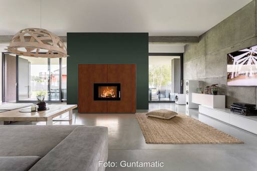 Ein Wohnzimmer mit einem Kaminofen. Er ist Teil eines Hybrid-Heizungssytems mit diesem Ofen, einer Wärmepumpe und einem Pelletskessel.